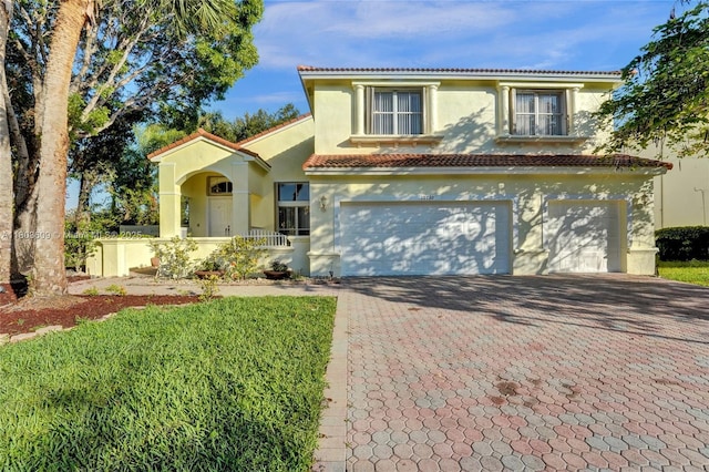mediterranean / spanish home with decorative driveway, stucco siding, an attached garage, and a tiled roof