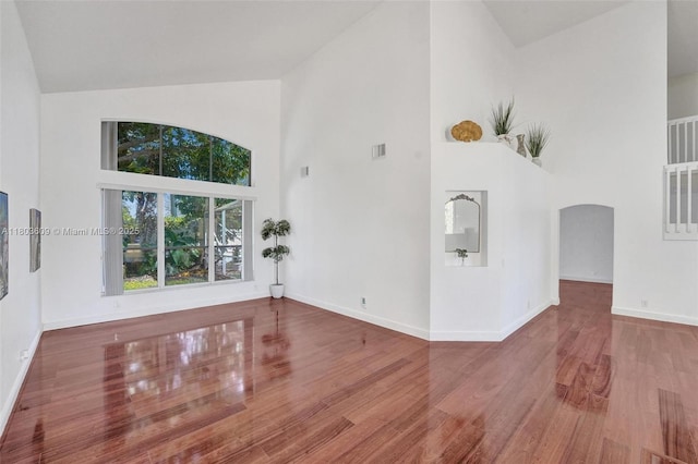 10730 NW 56th Ct, Coral Springs, FL 33076 - unfurnished living room with high vaulted ceiling, arched walkways, and wood finished floors