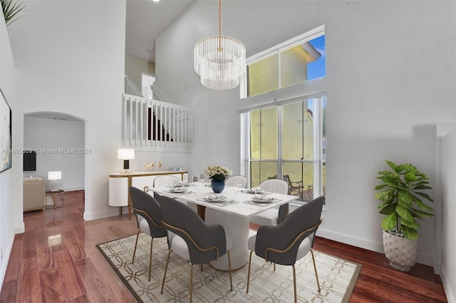 10730 NW 56th Ct, Coral Springs, FL 33076 - dining room featuring a towering ceiling, a chandelier, wood finished floors, and arched walkways