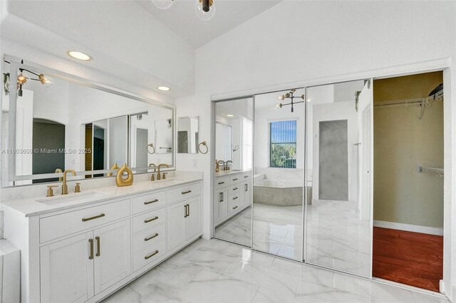 10730 NW 56th Ct, Coral Springs, FL 33076 - bathroom with double vanity, a tub, marble finish floors, a chandelier, and a walk in closet