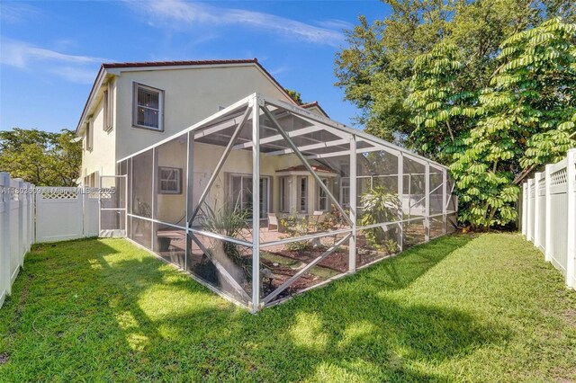 10730 NW 56th Ct, Coral Springs, FL 33076 - rear view of house with a fenced backyard, stucco siding, and glass enclosure