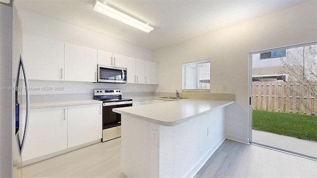 388 NW 12th Pl Unit 388, Florida City, FL 33034 - kitchen featuring stainless steel appliances, a sink, a peninsula, light countertops, and white cabinetry
