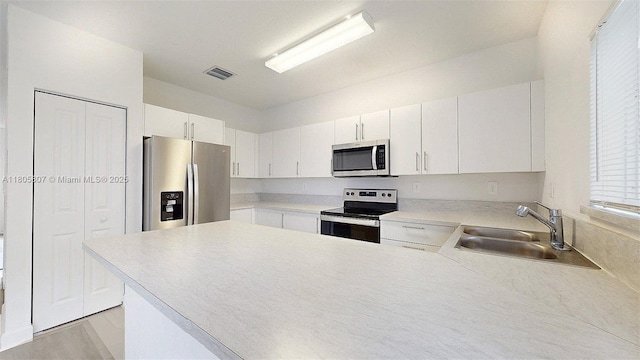 388 NW 12th Pl Unit 388, Florida City, FL 33034 - kitchen with stainless steel appliances, a sink, a peninsula, light countertops, and white cabinets