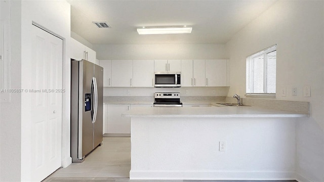 388 NW 12th Pl Unit 388, Florida City, FL 33034 - kitchen featuring appliances with stainless steel finishes, a sink, a peninsula, light countertops, and white cabinetry