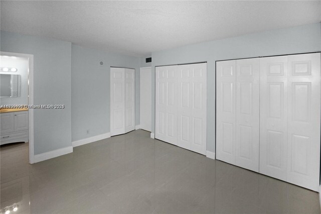 17021 N Bay Rd Unit 105, Sunny Isles Beach, FL 33160 - unfurnished bedroom featuring multiple closets, connected bathroom, and tile patterned floors