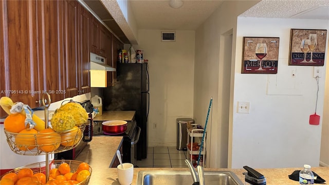 kitchen featuring under cabinet range hood, black electric range oven, tile patterned flooring, and light countertops