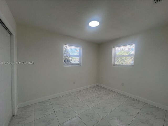 18740 NW 42nd Pl, Miami Gardens, FL 33055 - empty room featuring light marble finish floors, healthy amount of natural light, and baseboards