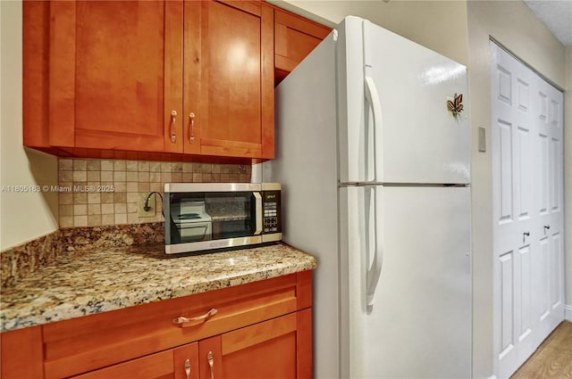 1561 NW 98th Ter, Pembroke Pines, FL 33024 - kitchen featuring freestanding refrigerator, tasteful backsplash, light stone countertops, and stainless steel microwave