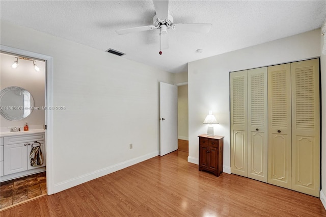 1561 NW 98th Ter, Pembroke Pines, FL 33024 - unfurnished bedroom featuring light wood-style floors, a closet, a textured ceiling, ensuite bath, and a sink