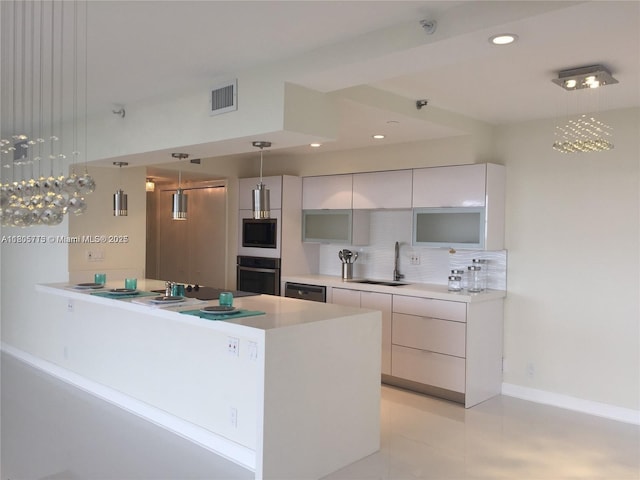 19707 Turnberry Way Unit 18D, Aventura, FL 33180 - kitchen featuring appliances with stainless steel finishes, a sink, modern cabinets, decorative backsplash, and light countertops