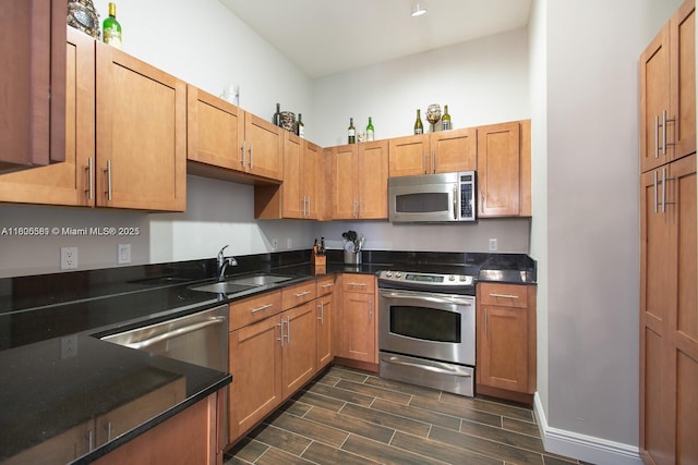 8395 SW 73rd Ave Unit 312, Miami, FL 33143 - kitchen featuring stainless steel appliances, a sink, dark wood finished floors, dark stone counters, and brown cabinets