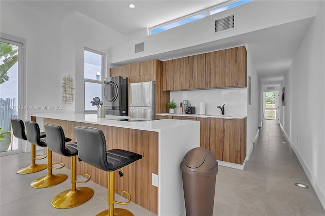 2345 SW 16th St, Miami, FL 33145 - kitchen with freestanding refrigerator, washer / clothes dryer, brown cabinets, modern cabinets, and a breakfast bar area