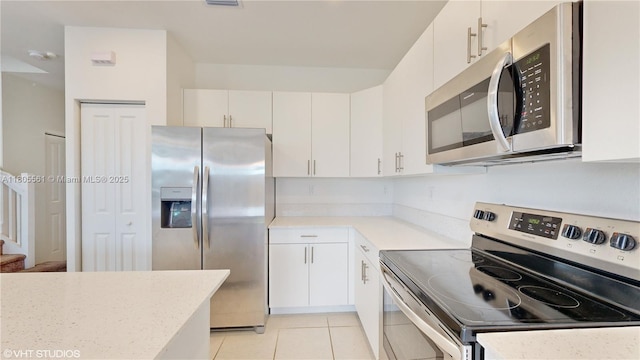 10004 SW 231st Ln, Miami, FL 33190 - kitchen featuring appliances with stainless steel finishes, light tile patterned flooring, white cabinets, and light stone counters