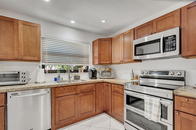 1541 NW 92nd Ave Unit 186, Pembroke Pines, FL 33024 - kitchen featuring stainless steel appliances, a sink, brown cabinetry, recessed lighting, and light stone countertops