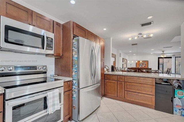 1541 NW 92nd Ave Unit 186, Pembroke Pines, FL 33024 - kitchen featuring appliances with stainless steel finishes, a peninsula, ceiling fan, light tile patterned flooring, and light stone counters