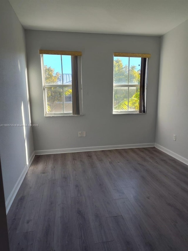 unfurnished room featuring dark wood-style flooring and baseboards