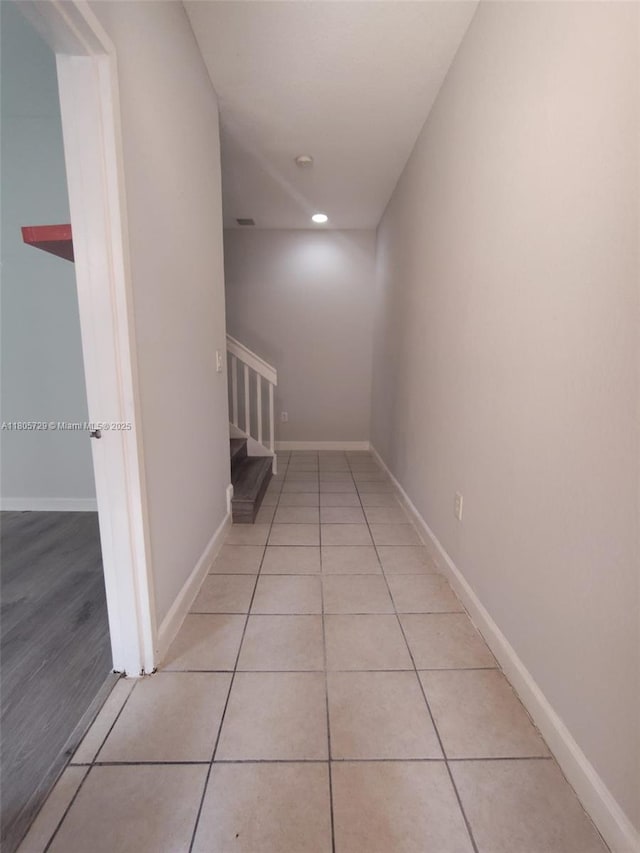 hall featuring baseboards, light tile patterned floors, and recessed lighting