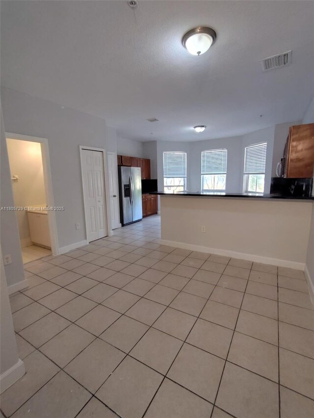 unfurnished living room featuring baseboards and light tile patterned floors