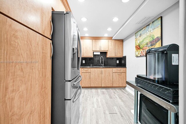 2655 Collins Ave Unit 1501, Miami Beach, FL 33140 - kitchen featuring stainless steel refrigerator with ice dispenser, light wood-style flooring, light brown cabinets, dark countertops, and decorative backsplash