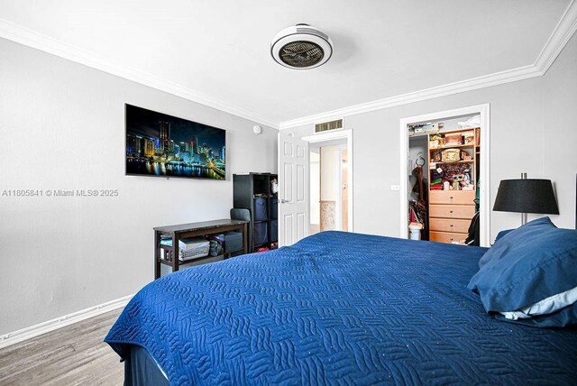 2655 Collins Ave Unit 1501, Miami Beach, FL 33140 - bedroom featuring ornamental molding, baseboards, wood finished floors, and a walk in closet