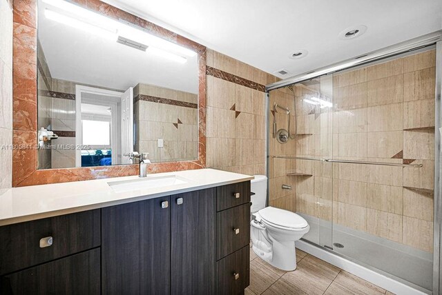 2655 Collins Ave Unit 1501, Miami Beach, FL 33140 - bathroom featuring a shower stall, tile walls, toilet, vanity, and tile patterned floors