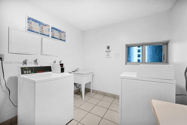 2655 Collins Ave Unit 1501, Miami Beach, FL 33140 - communal laundry room with washing machine and dryer, a textured ceiling, light tile patterned floors, and baseboards