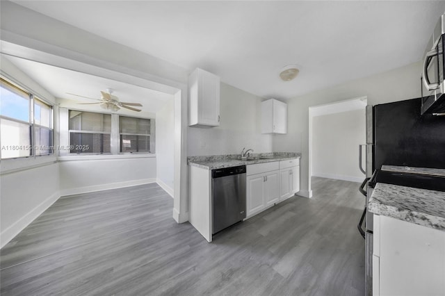 kitchen with stainless steel appliances, a sink, white cabinetry, wood finished floors, and baseboards