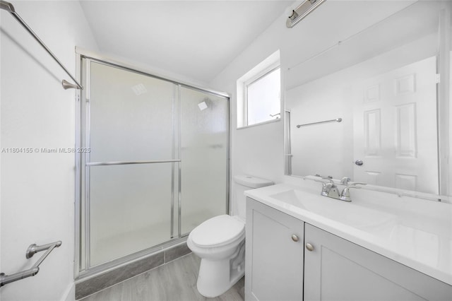 bathroom with toilet, a shower stall, vanity, and wood finished floors