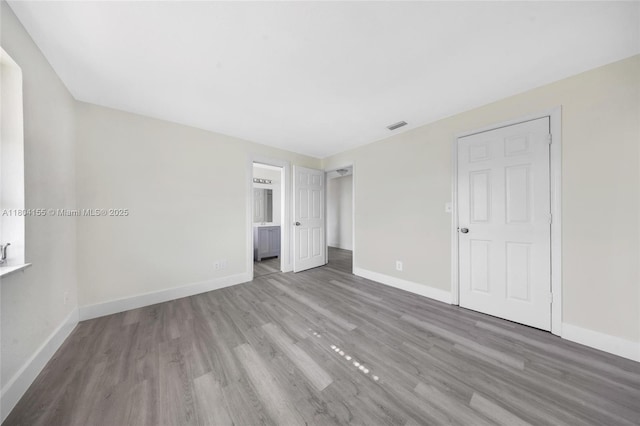 unfurnished bedroom with wood finished floors and baseboards