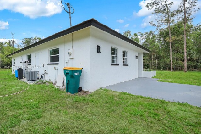 3973 4th Ave SE, Naples, FL 34117 - view of side of property with central AC, stucco siding, a lawn, and a patio area