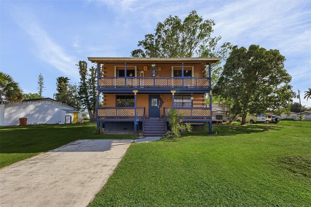 4070 E River Ft, Myers, FL 33916 - view of front facade with covered porch, a front yard, a balcony, and concrete driveway