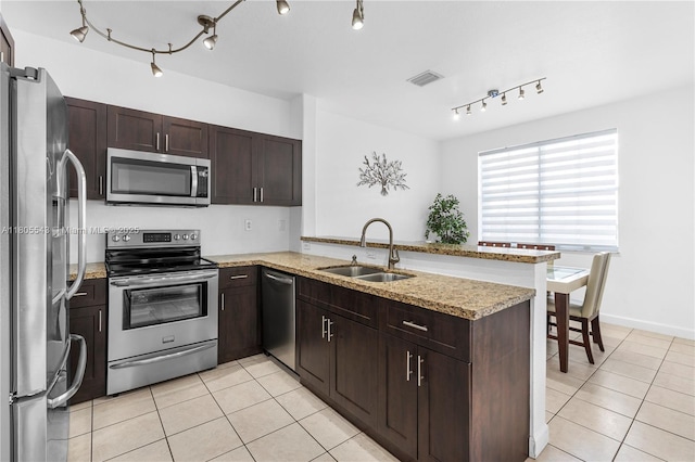 kitchen with stainless steel appliances, a sink, light tile patterned floors, and a peninsula