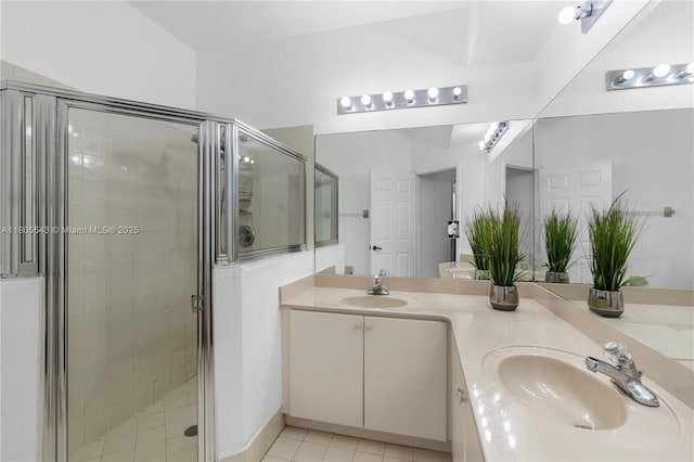 bathroom with a stall shower, double vanity, and tile patterned floors