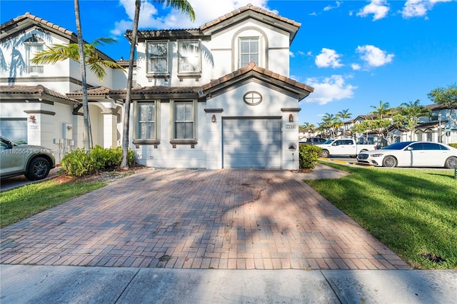 view of front of property with a tile roof, stucco siding, decorative driveway, a front yard, and an attached garage