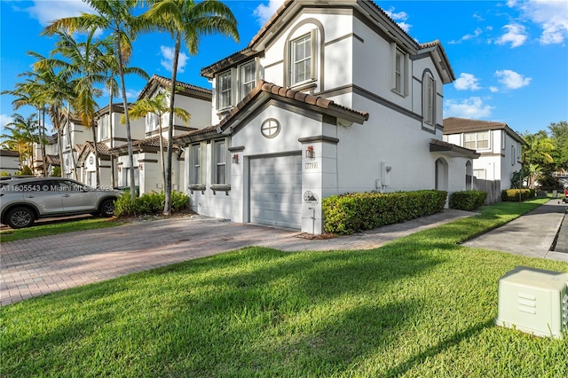 view of front of house featuring a tile roof, an attached garage, driveway, and a front lawn