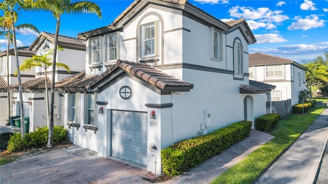 view of side of property featuring a tiled roof, a garage, and stucco siding