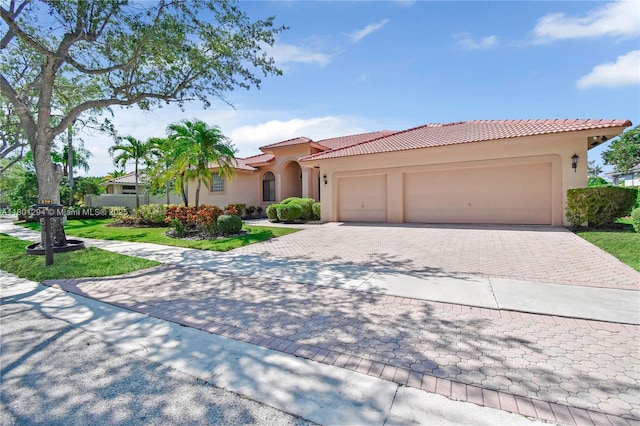 2701 Edgewater Ct, Weston, FL 33332 - mediterranean / spanish house featuring stucco siding, a tiled roof, a garage, decorative driveway, and a front lawn