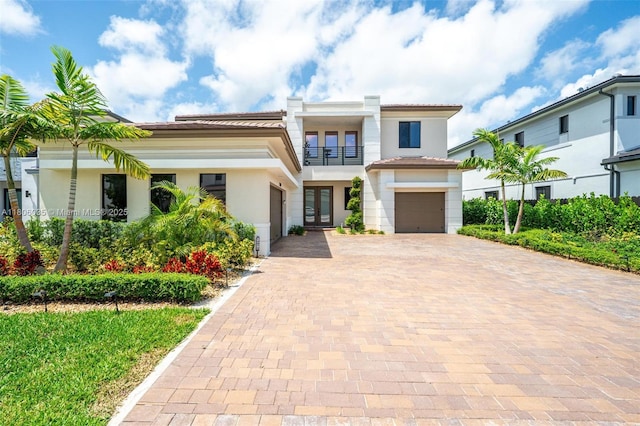 view of front of property with french doors, a balcony, decorative driveway, and stucco siding