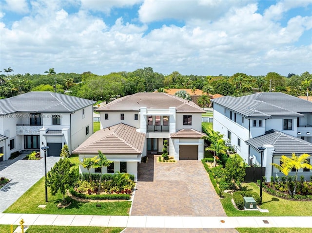view of front of property featuring decorative driveway, a tiled roof, a garage, a balcony, and a residential view