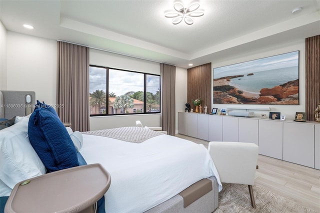 bedroom featuring light wood finished floors, a tray ceiling, and recessed lighting