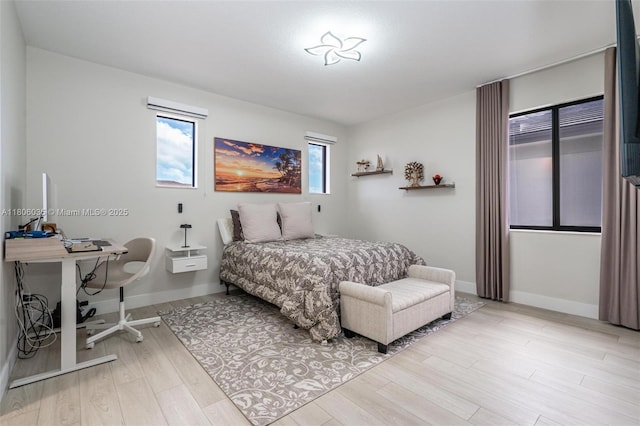 bedroom featuring light wood-style flooring, an office area, and baseboards