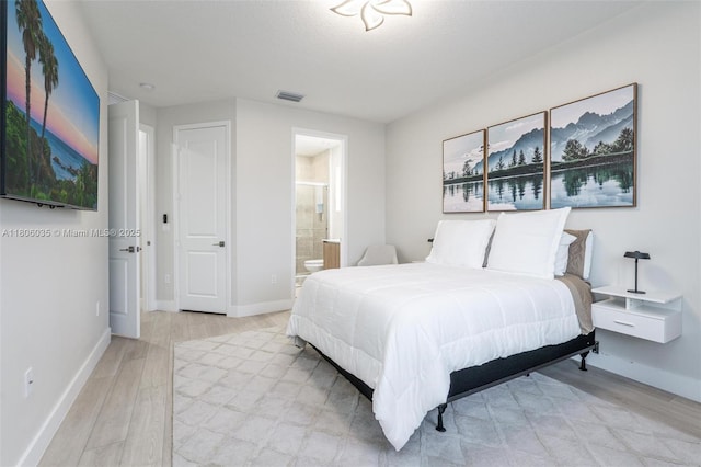 bedroom with light wood-style floors, baseboards, and connected bathroom