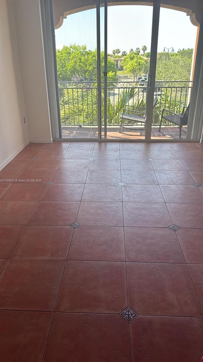 tiled empty room featuring healthy amount of natural light and baseboards