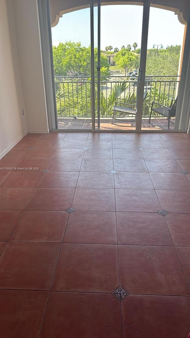 tiled empty room featuring healthy amount of natural light and baseboards