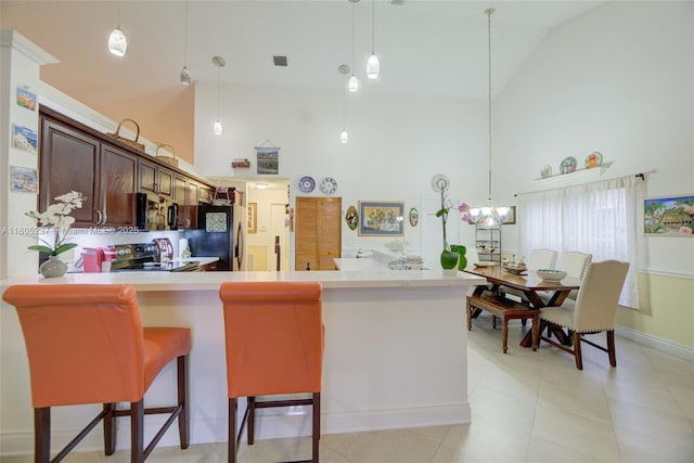 596 NW 164th Ave, Pembroke Pines, FL 33028 - kitchen with appliances with stainless steel finishes, high vaulted ceiling, light countertops, hanging light fixtures, and a kitchen bar