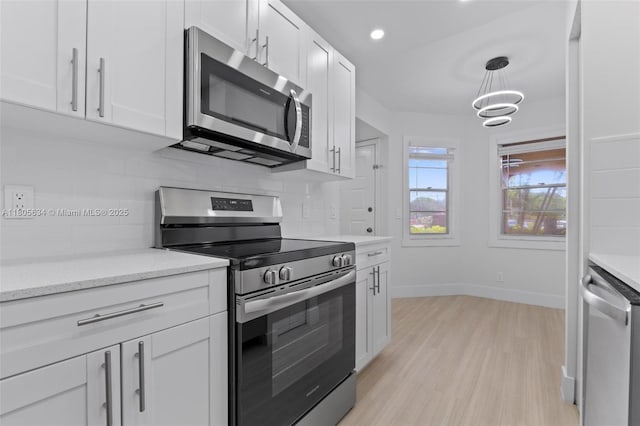 1300 SW 124th Ter Unit 107P, Pembroke Pines, FL 33027 - kitchen with stainless steel appliances, backsplash, light wood-type flooring, baseboards, and white cabinetry