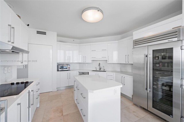 300 S Pointe Dr Unit 1505, Miami Beach, FL 33139 - kitchen with built in fridge, a sink, black electric stovetop, under cabinet range hood, and light countertops