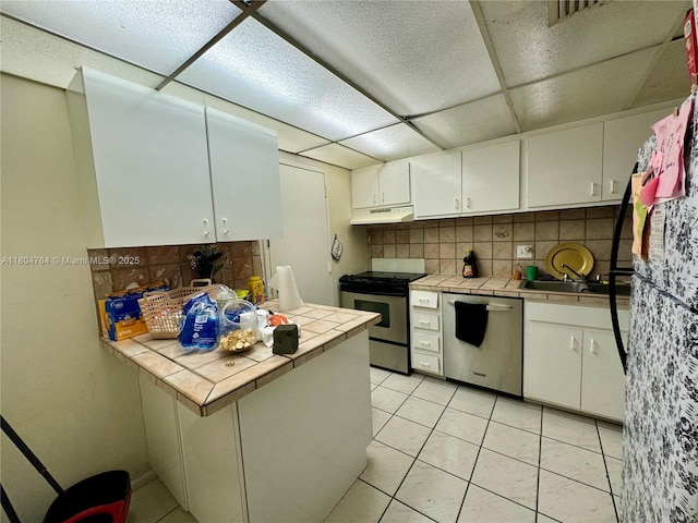 3660 Inverrary Dr Unit 2W, Lauderhill, FL 33319 - kitchen featuring stainless steel appliances, tile countertops, under cabinet range hood, decorative backsplash, and white cabinets