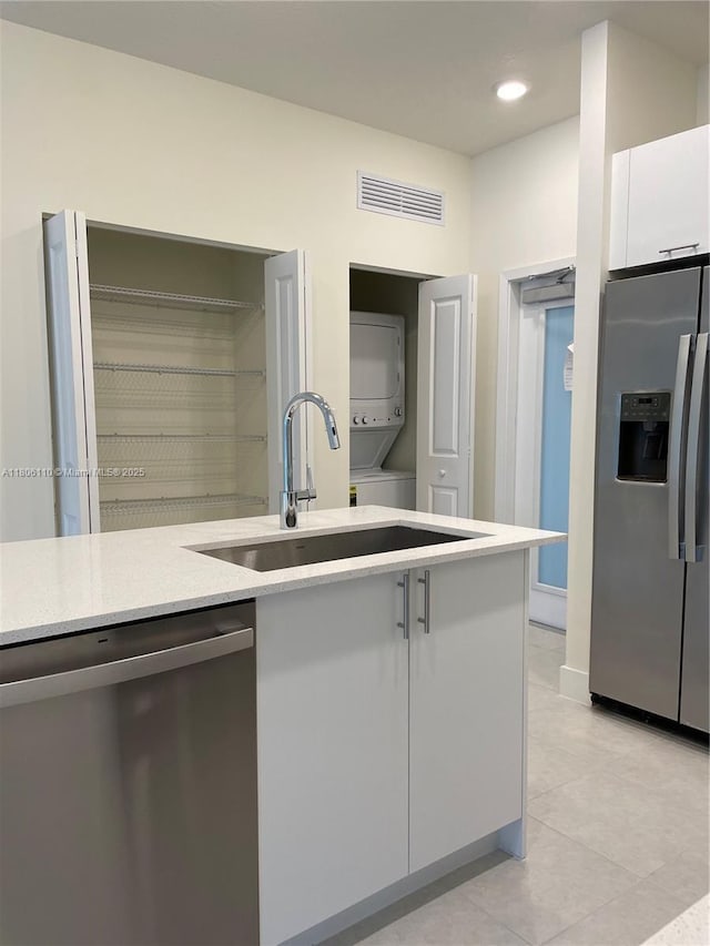 8001NW 41st St Unit F-108, Doral, FL 33166 - kitchen featuring stainless steel appliances, stacked washer and clothes dryer, a sink, light tile patterned flooring, and white cabinets