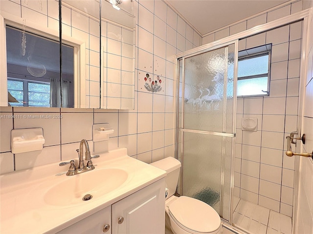 bathroom with tile walls, a stall shower, toilet, vanity, and tasteful backsplash